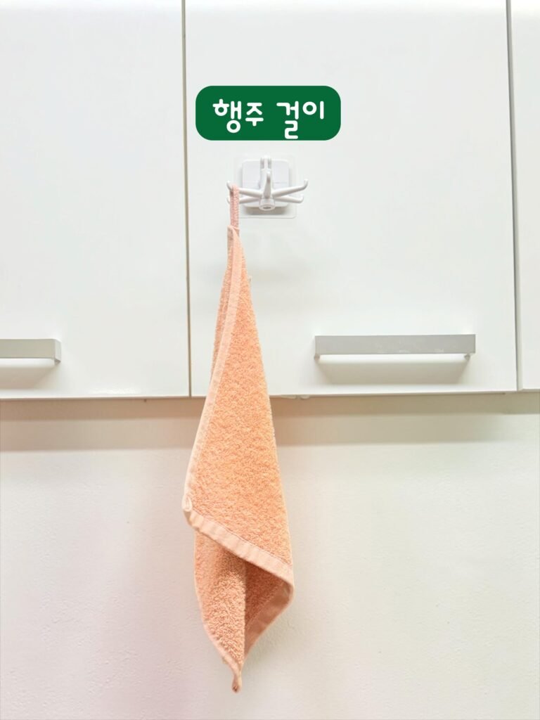주방 상부장 회전식 접착 후크에 행주를 걸어둔 모습
